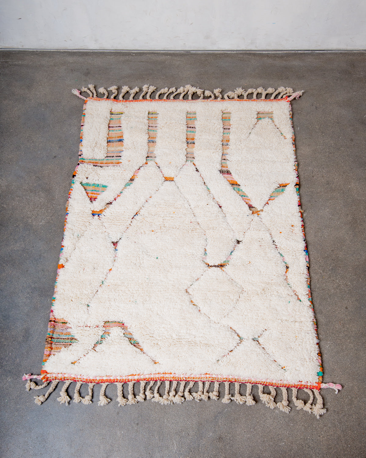 Beniourain rug in cream wool laying on concrete studio floor.